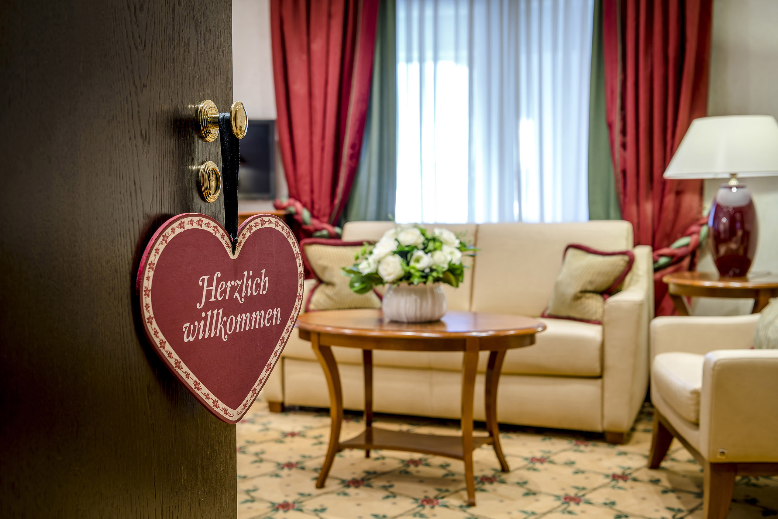 Einblick durch die geöffnete Zimmertür in einen Wohnbereich mit Sofa und Stühlen